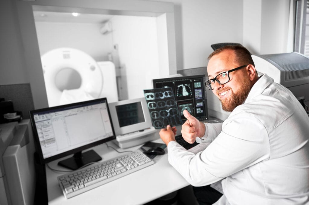 Radiolog przy konsoli sterowniczej tomografu podczas badania