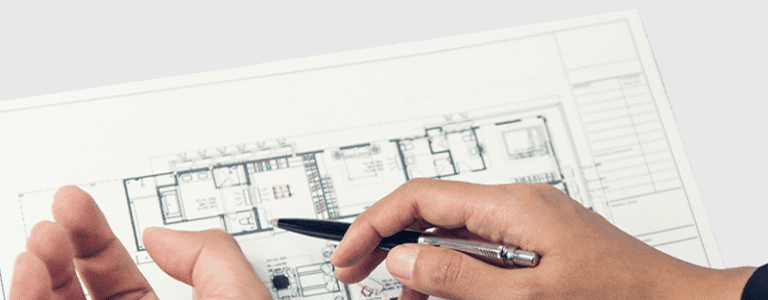 Ręce z długopisem nad planem architektonicznym pracowni medycznej